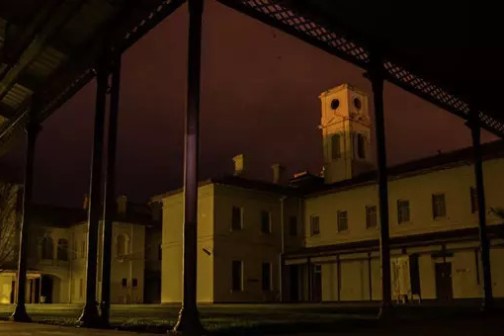 Dimly lit courtyard with historic buildings under a dark purple sky.
