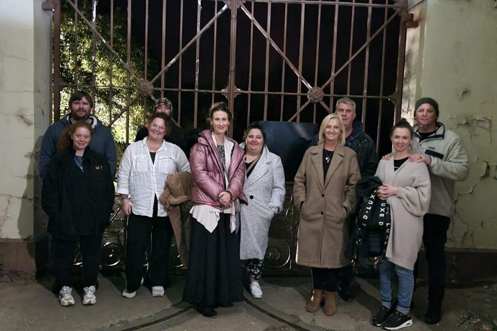 Group of people posing in front of an ornate metal gate.