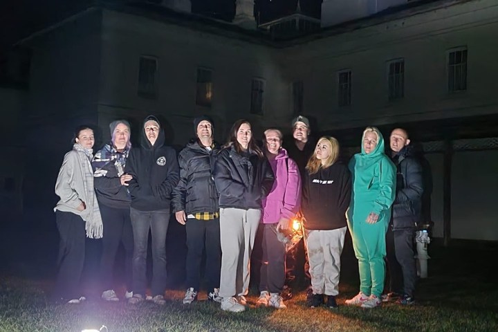Group of people posing outdoors at night with a building in the background.